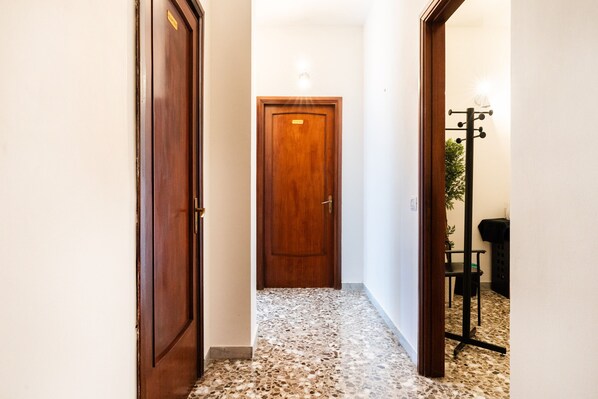 Un couloir avec une porte en bois, un sol carrelé et un porte-manteau.