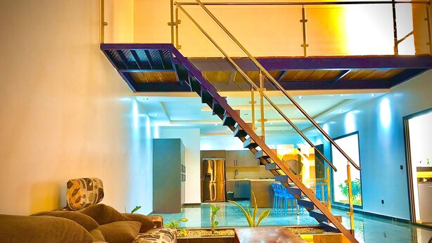 A modern living room with a staircase, a glass coffee table, and a sofa. - Architect-designed house in Nianing Peace and relaxation (NIANING)