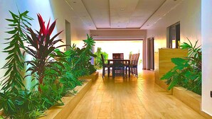 A modern interior with a wooden floor, a dining area with chairs, and potted plants. - Architect-designed house in Nianing Peace and relaxation (NIANING)