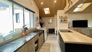 Une cuisine moderne avec des meubles en bois, un plan de travail noir, un four encastré et une grande fenêtre.