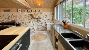Une cuisine avec un mur en pierre, un plafond en bois et une lucarne.