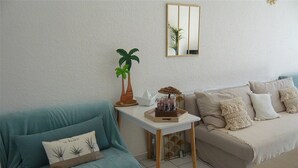 A living room with a teal sofa, a beige sofa, a small white table, and a mirror on the wall. - Beautiful apartment with terrace for 4 people, near beach in Port Camargue (Port Camargue)