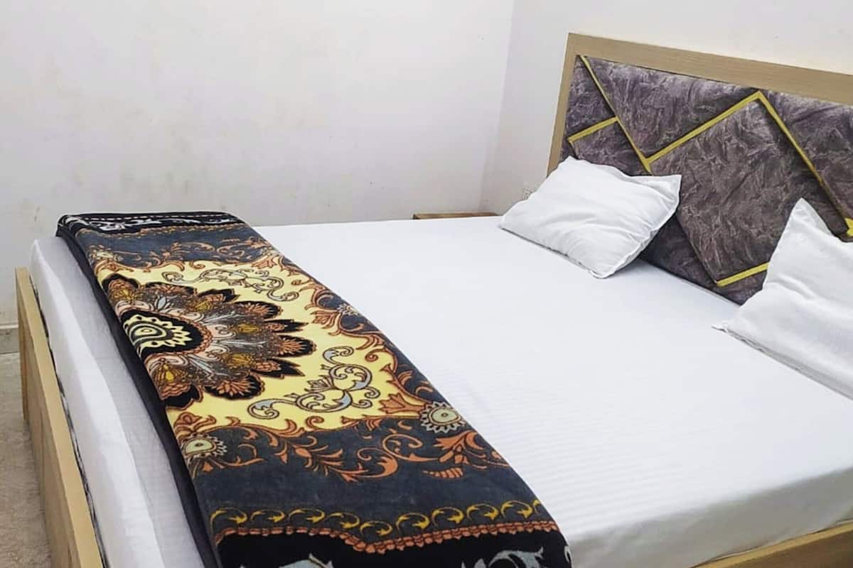 A bed with a patterned bedspread, white pillows, and a headboard with geometric designs.