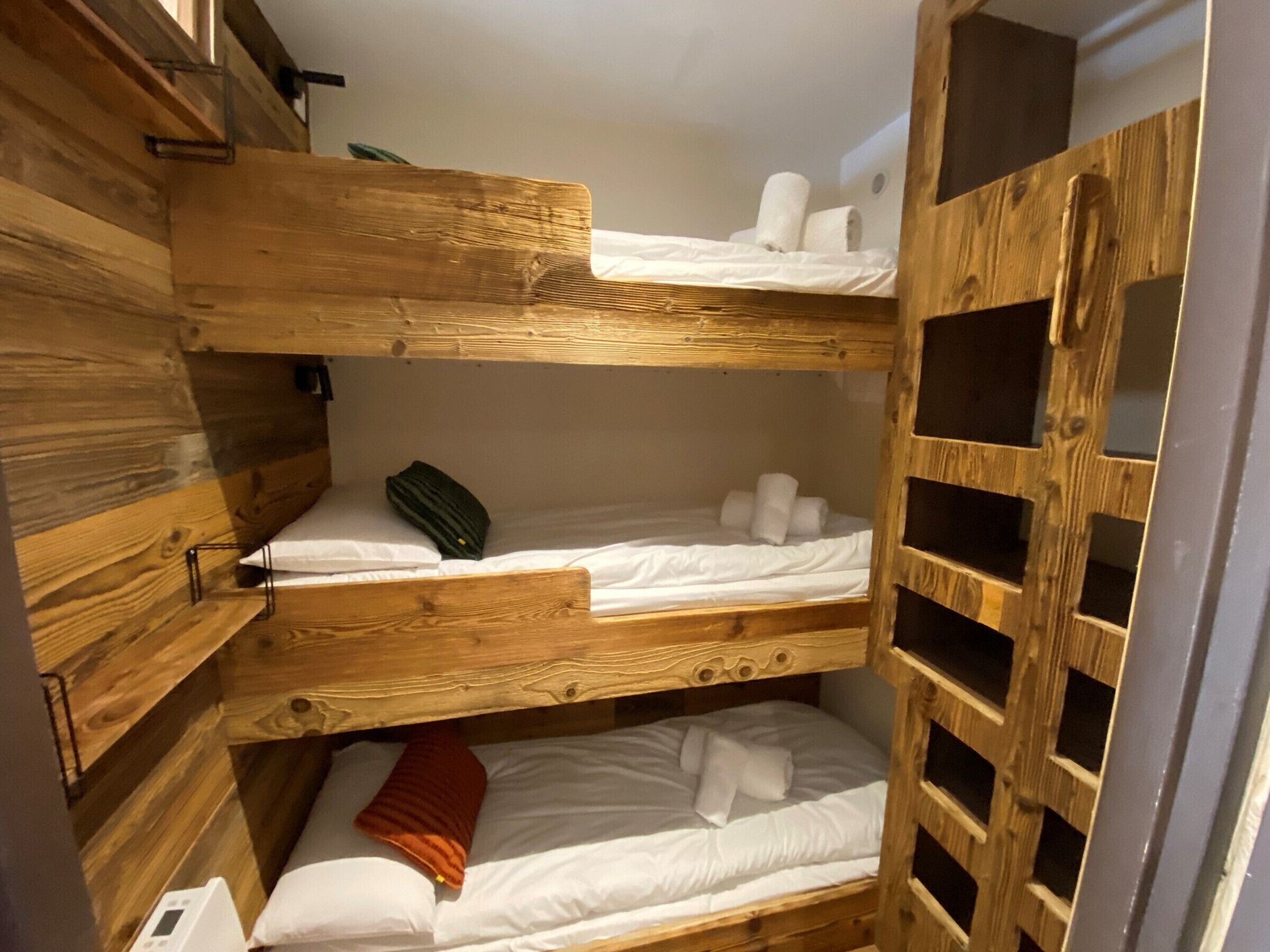 A bunk bed room with wooden walls and a built-in wardrobe.