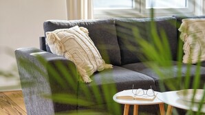 Ein modernes Wohnzimmer mit grauem Sofa, einem weißen Beistelltisch und einem Buch.