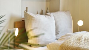 Ein ordentlich bezogenes Bett mit Kissen und einer Nachttischlampe.