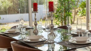 A dining table set for four with candles, clear glassware, and plates. - Villa Naturis (Portimão)