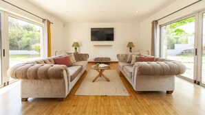 A spacious living room with two plush sofas, a coffee table, and a flat-screen TV on the wall. - Villa Naturis (Portimão)