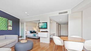 Un salon moderne comprenant un canapé, un pouf et un coin repas avec des chaises et une table.