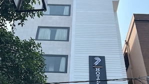 Ein Hotel-Schild mit dem Namen "HOTEL SEVENS" an einem weißen Gebäude.
