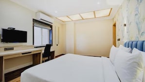 Ein Hotelzimmer mit einem Bett, einem Schreibtisch mit Fernseher und einem Fenster mit Jalousien.