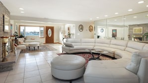 A spacious living room with a large white sectional sofa, a round coffee table, and a fireplace.