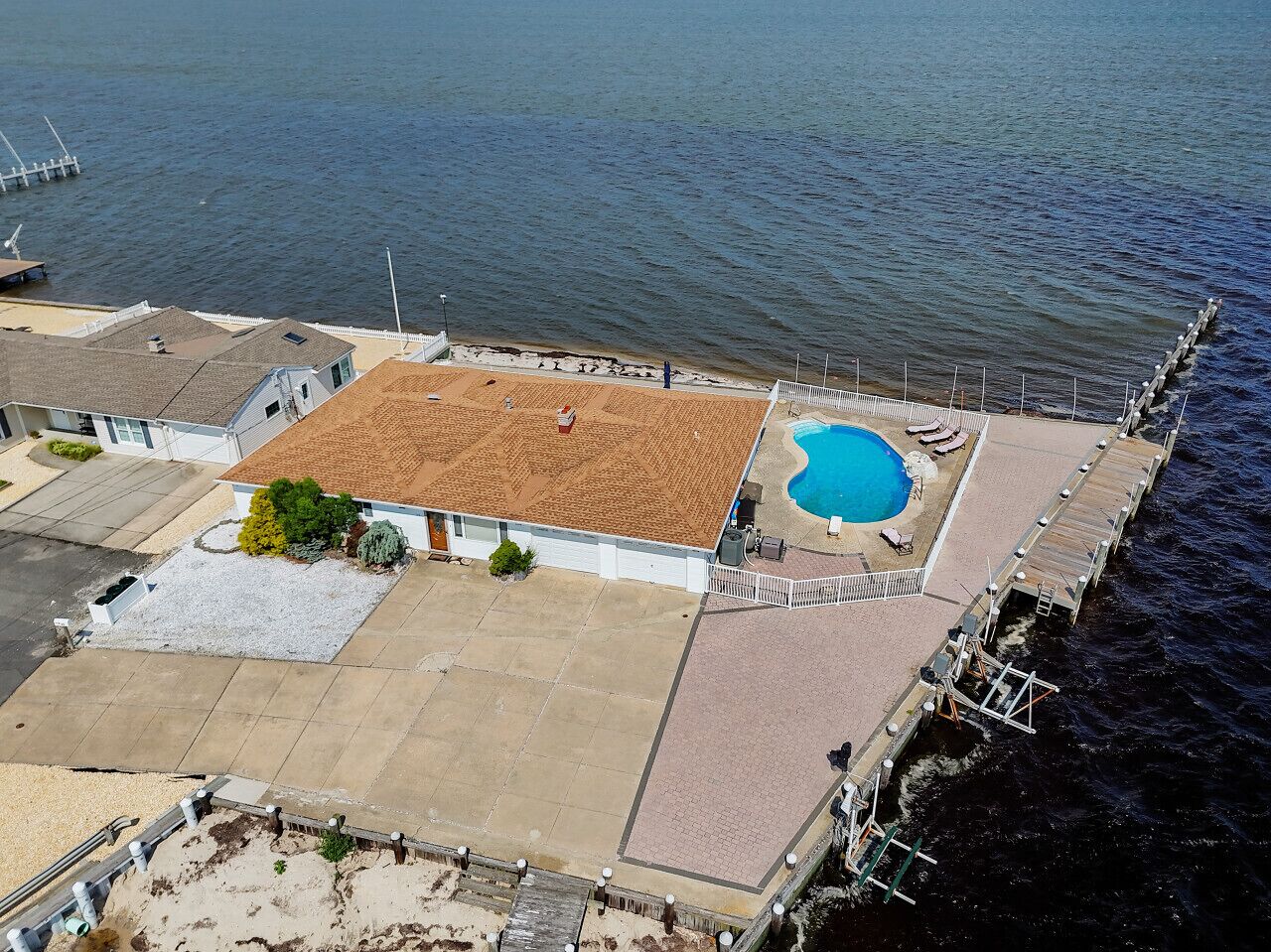 Ein Anwesen direkt am Wasserufer mit Schwimmbad, überdachter Terrasse und Bootsanleger.