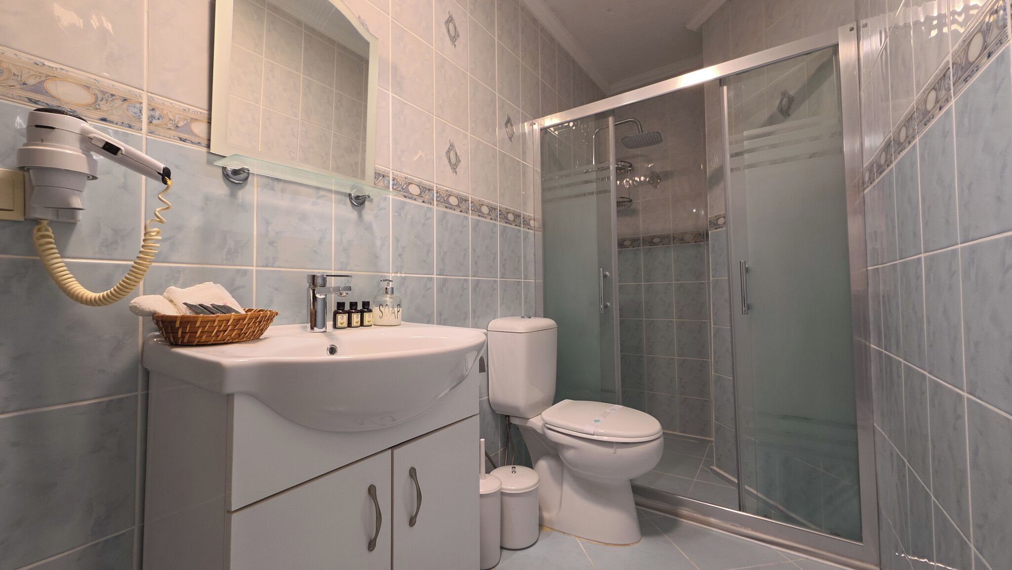 Un baño con lavamanos blanco, inodoro, cabina de ducha y teléfono.