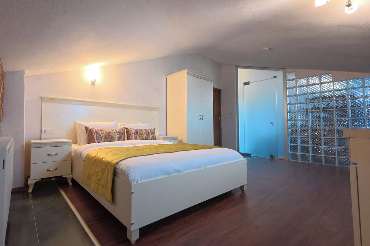Une chambre à coucher comprenant un lit, des tables de chevet, une armoire et un radiateur.