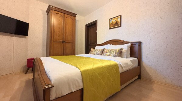 A bedroom with a bed, wooden wardrobe, a door, a painting, and a red object on the floor. - Casa Villa By Kirte (Eceabat)