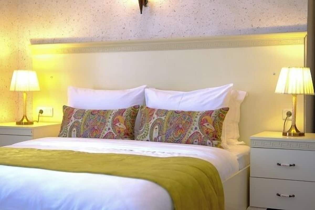 Une chambre d’hôtel avec un lit, deux tables de chevet et deux lampes.