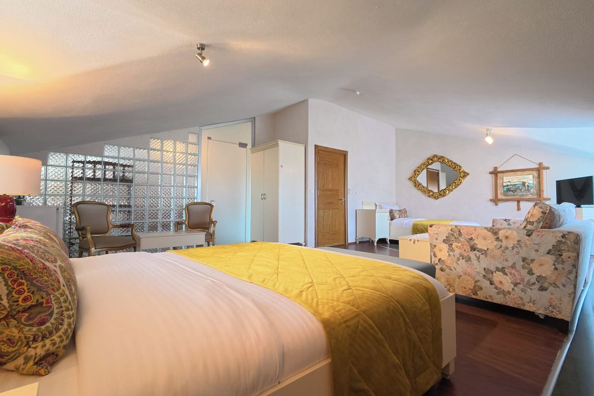 Une chambre d’hôtel avec un grand lit, un bureau, une chaise, une télévision et un miroir.