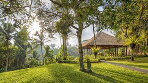 A lush garden with a thatched-roof gazebo, a pathway, and tropical vegetation. - The Allure Ubud Villas & Spa crafted by freshWater Asia (Ubud)
