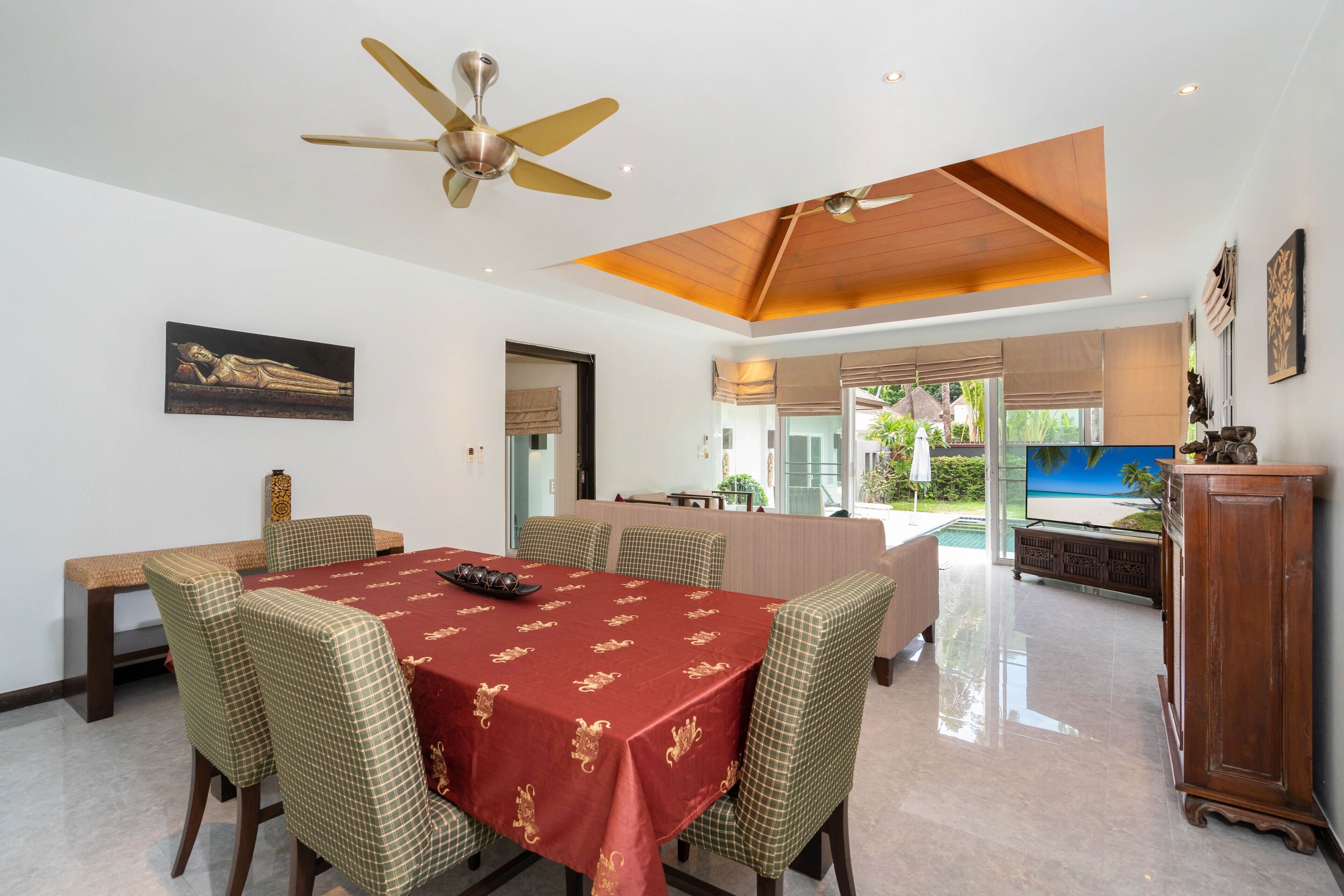 A dining area with a red tablecloth, checkered chairs, and a ceiling fan.