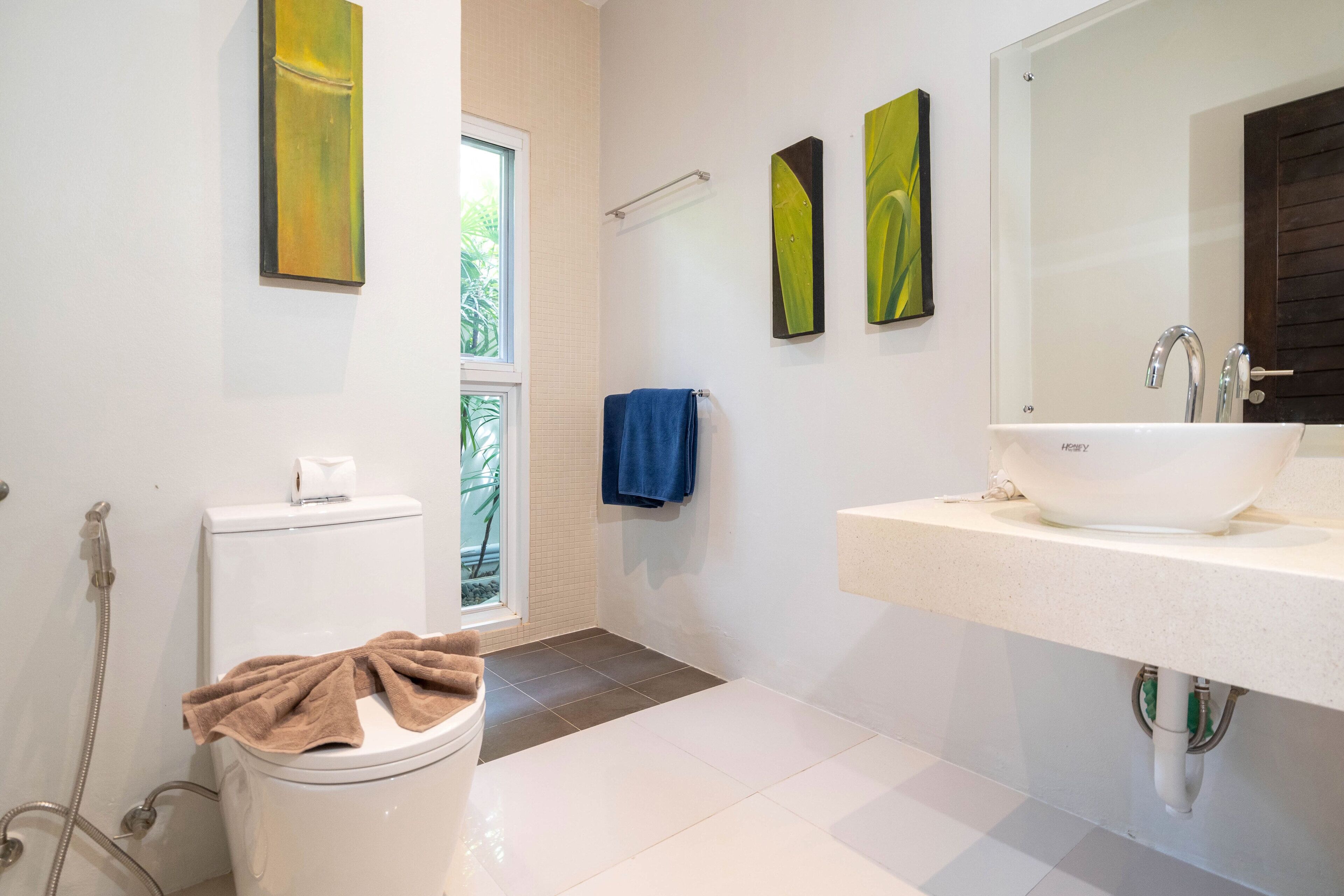 Un bagno moderno con toilette, bidet, lavandino e uno specchio grande.
