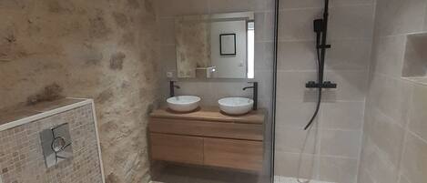Un bagno con il water, due lavandini, una doccia e uno specchio.