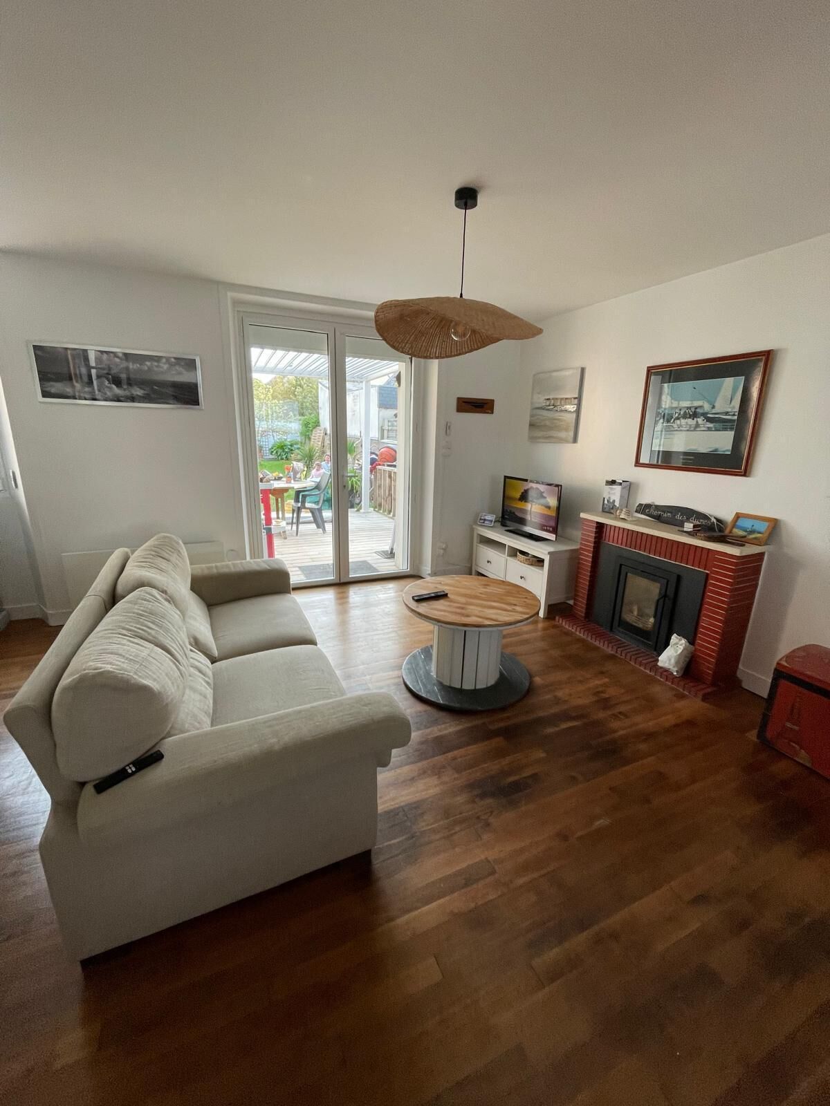 A living room with a white sofa, a round wooden coffee table, a fireplace, and a dining area with a table and chairs.