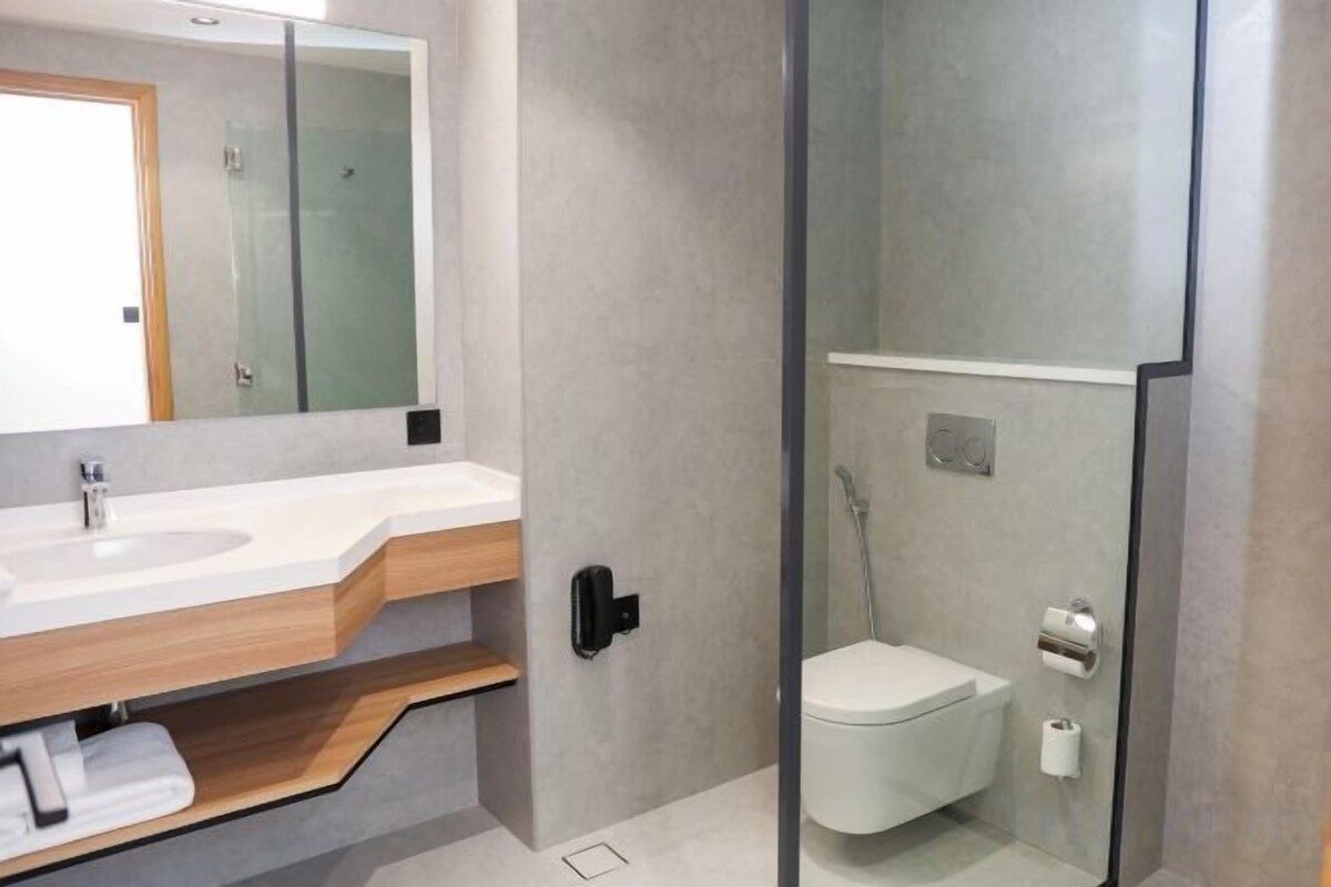 Een moderne badkamer met een wastafel, wastafelmeubel, spiegel en een apart toilet.
