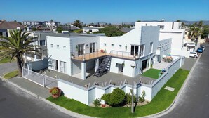 A modern two-story building with a flat roof, large windows, and a balcony. - A peaceful and safe area, just minutes from the beach, bars, and restaurants. (Cape Town)
