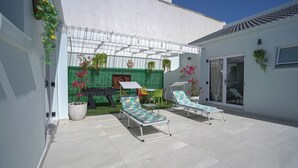A patio with two lounge chairs, a small table, and a grill area. - A peaceful and safe area, just minutes from the beach, bars, and restaurants. (Cape Town)