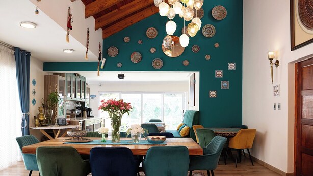 A dining area with a wooden table, teal chairs, and a chandelier. - A peaceful and safe area, just minutes from the beach, bars, and restaurants. (Cape Town)