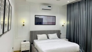 Une chambre moderne équipée d’un lit, de tables de chevet, d’un climatiseur et d’un système d’éclairage fixé au mur.