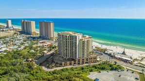A coastal hotel with multiple high-rise buildings, a beach, and a parking area.