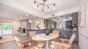 Une cuisine moderne avec une table à manger ronde, des chaises en bois et un mur d’accent en pierre.