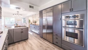 Une cuisine moderne avec des meubles de couleur grise, des appareils électroménagers en acier inoxydable et un plancher en bois.