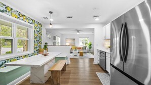 Una cocina moderna con un refrigerador de acero inoxidable, una encimera de mármol y un banco de madera.