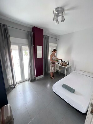 Una camera d'albergo con un letto, una scrivania, una sedia e una finestra con tende.