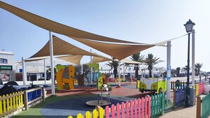 A playground with colorful play structures and a shaded area. - Casa del Sol, heated pool quiet place (Playa Blanca)