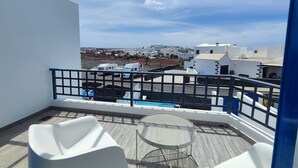 A balcony with a view of a coastal town, white chairs, and a pool. - Casa del Sol, heated pool quiet place (Playa Blanca)