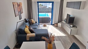 A modern living room with a sofa, a dining table, and a TV. - Casa del Sol, heated pool quiet place (Playa Blanca)