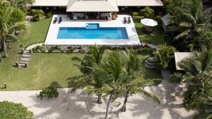 A large house with a swimming pool, surrounded by palm trees and a sandy area. - Mokusiga Villas Tolu - Private Beachfront Villa (Korolevu)