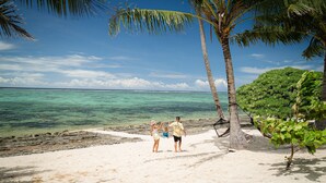 A beach with clear turquoise water, palm trees, and a rocky shoreline. - Mokusiga Villas Tolu - Private Beachfront Villa (Korolevu)
