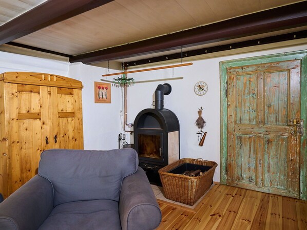 Une pièce chaleureuse avec un canapé en bois, une cheminée, une porte verte et une armoire rustique en bois.
