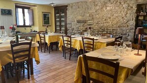 A dining area with multiple tables set for guests, featuring stone walls and a rustic ambiance. - Locanda di Federico (Casteldelci)