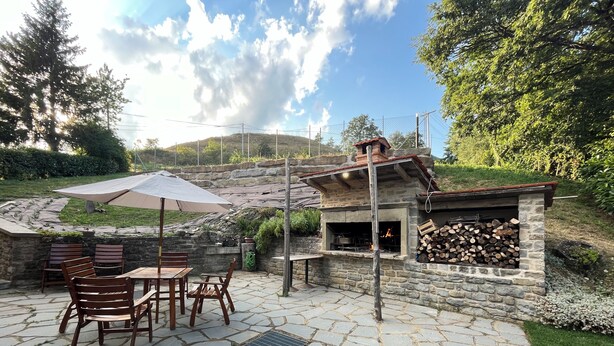 A stone patio with a fire pit and outdoor seating. - Locanda di Federico (Casteldelci)