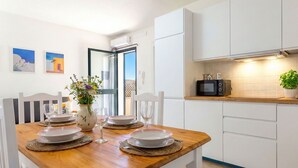 A dining area with a wooden table set for four, white chairs, and a vase with flowers.