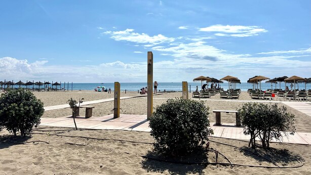 A beach with sun loungers, umbrellas, and a clear sky. - ZUR Boutique Hostel (Fuengirola)