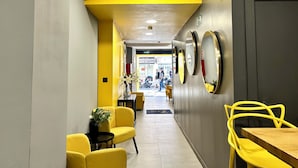 A hallway with yellow chairs, a small table with a plant, and a door with a fire safety sign. - ZUR Boutique Hostel (Fuengirola)