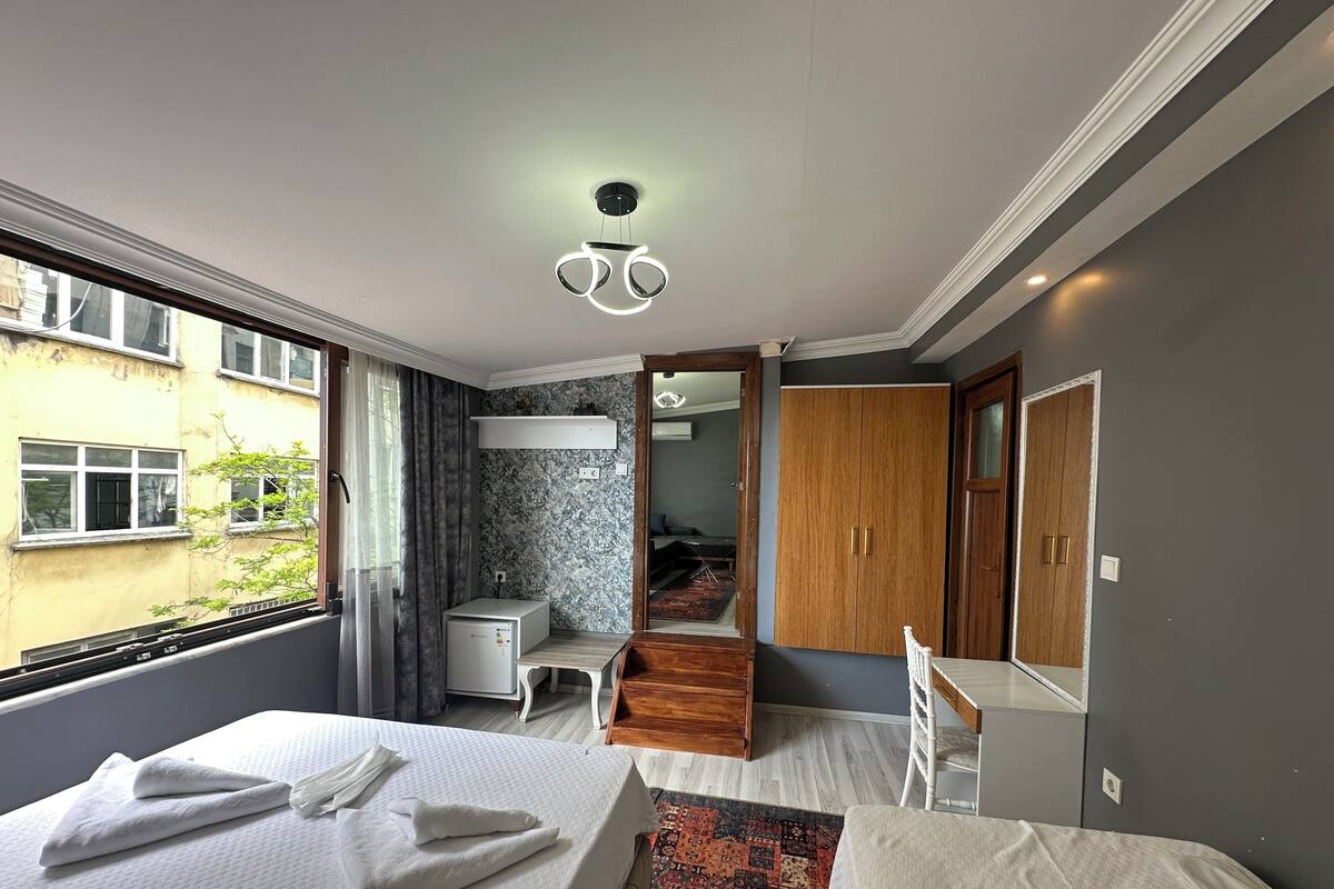 A modern hotel room with a large bed, a desk, a wardrobe, and a view of the outside.