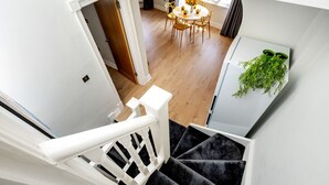 A staircase with a white railing leading to a dining area with a round table and chairs.
